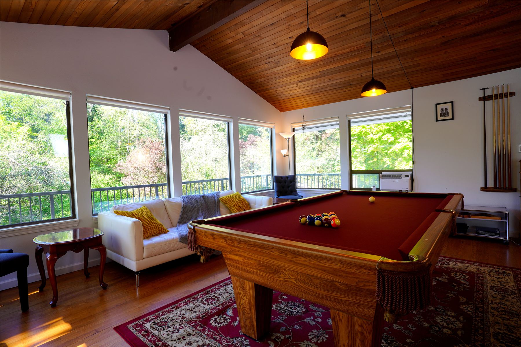 Bright game room with vaulted cedar ceiling, pool table and white leather sofa