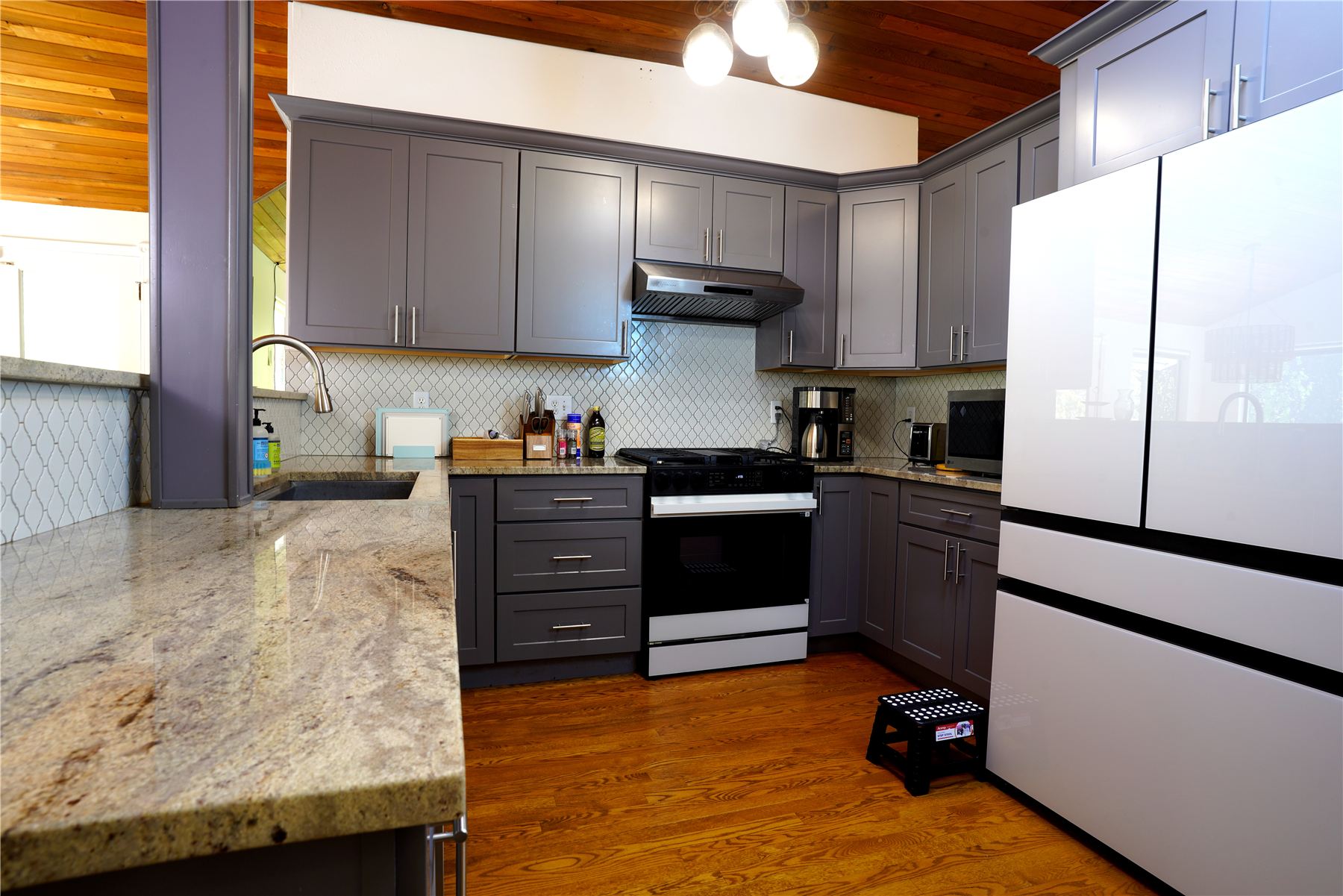 Kitchen with granite peninsula, gas range and white French-door refrigerator