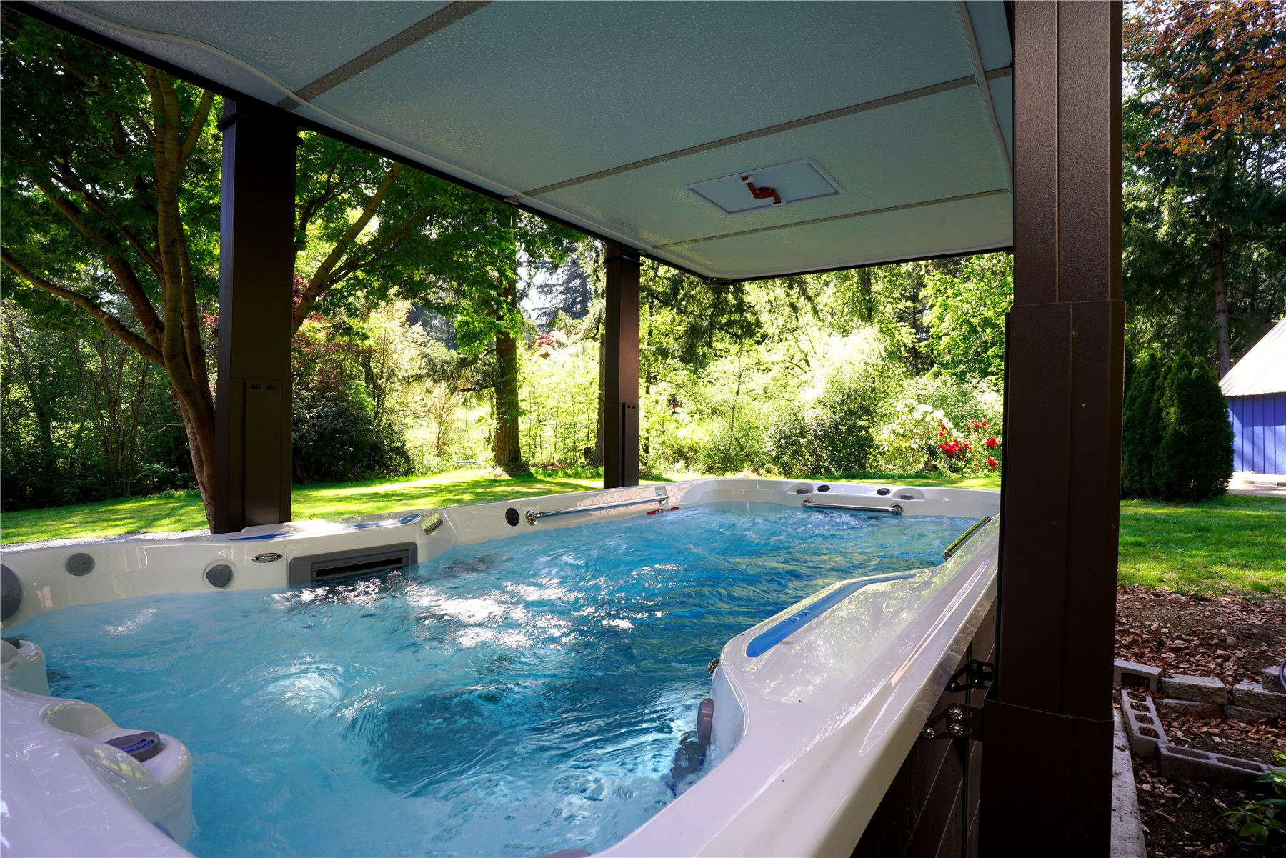 Covered swim spa with clear blue water overlooking the yard